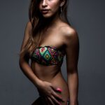 Isadora in gemustertem Bikini vor grauem Studiohintergrund, sportliche Silhouette
