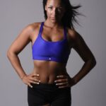 Isadora in Sportkleidung, Ganzkörperaufnahme vor grauem Studiohintergrund, trainierte Figur