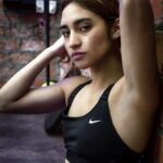 Isadora im Sport-BH vor einer Backsteinwand, urbanes Tageslicht, athletische Figur