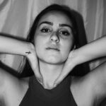 Isadora mit dunklem Haar und erhobenen Armen, sportliches Schwarzweiß-Portrait im Tanktop